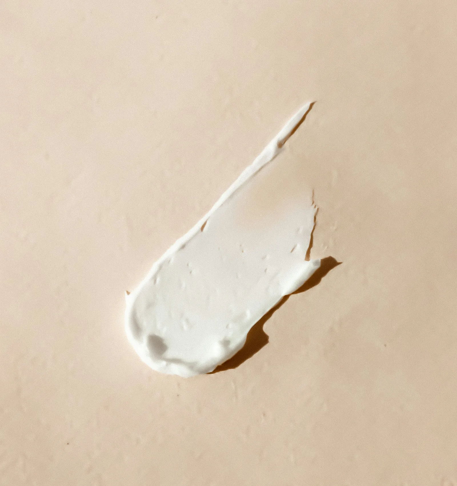 Smear of thick white cream on a textured beige surface